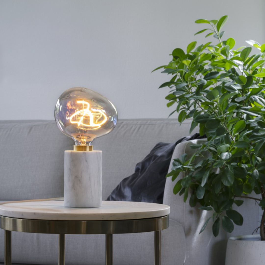 Bubblan LED glödlampa på vit marmor bordslampa i modern vardagsrumsmiljö.