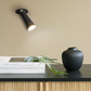 Modern svart bordslampa med vridbar armatur, LED-belysning och uppladdningsbart batteri, placerad på skrivbord.