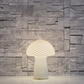 Vit glaslampa i svampform med sneda ränder och LED-belysning. Vit bordslampa i glas. Snygg bordslampa i vit färg. Svamplampa i glas.