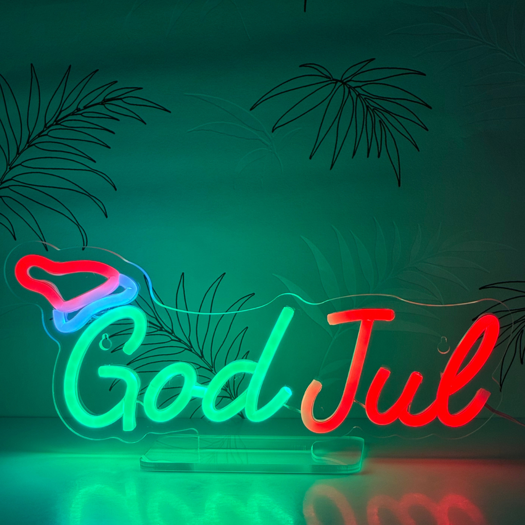 God Jul neon skylt med rött, grönt och blått LED-ljus. Färgglad LED-skylt med God Jul-text och tomteluva i neonstil. Juldekoration i plexiglas med LED-belysning för vägg eller bord. USB-driven God Jul-skylt med färgskiftande LED-ljus för inomhusbruk.