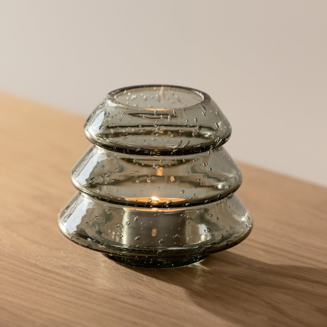 Grön glaslykta med bubblor som sprider mjukt sken från värmeljus. Granlykta Grönt Glas – unik handgjord ljuslykta i glas.