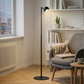 Trådlös svart golvlampa med LED-belysning placerad i vardagsrum vid fåtölj